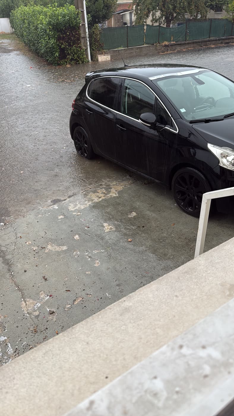 Voiture stationnée les roues dans l'eau rue de la Poste lors de l'inondation du 15 août 2026 à Gourdan-Polignan