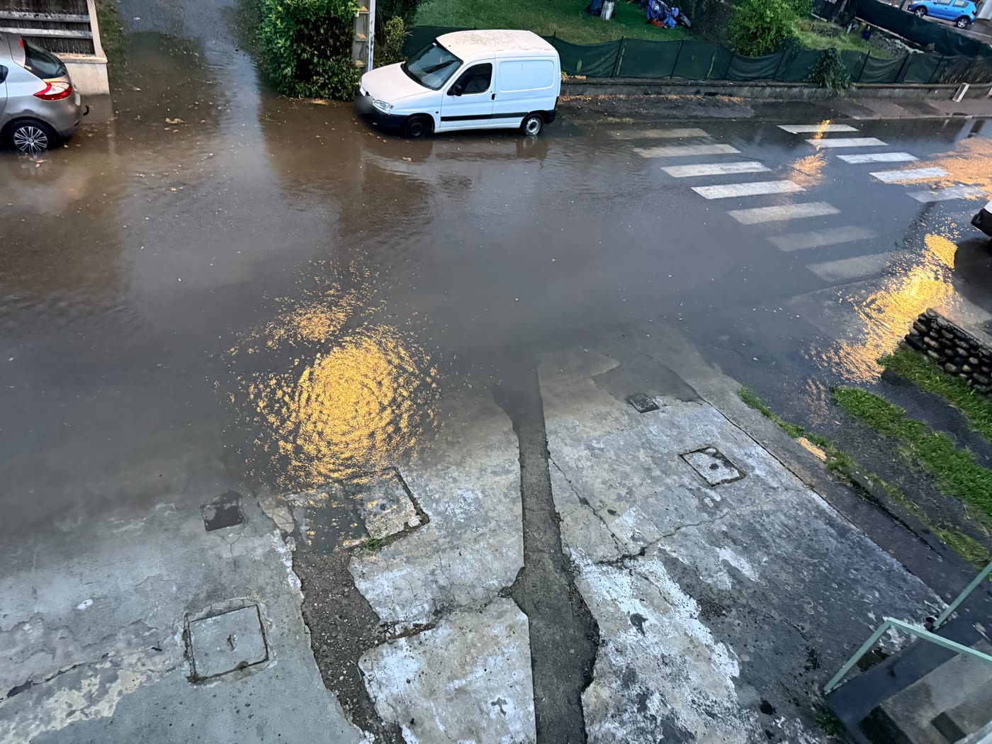 Carrefour de la rue de la Poste à Gourdan-Polignan entièrement recouvert d'eau boueuse lors de l'orage du 20 août 2026, le passage piéton disparaît sous l'eau
