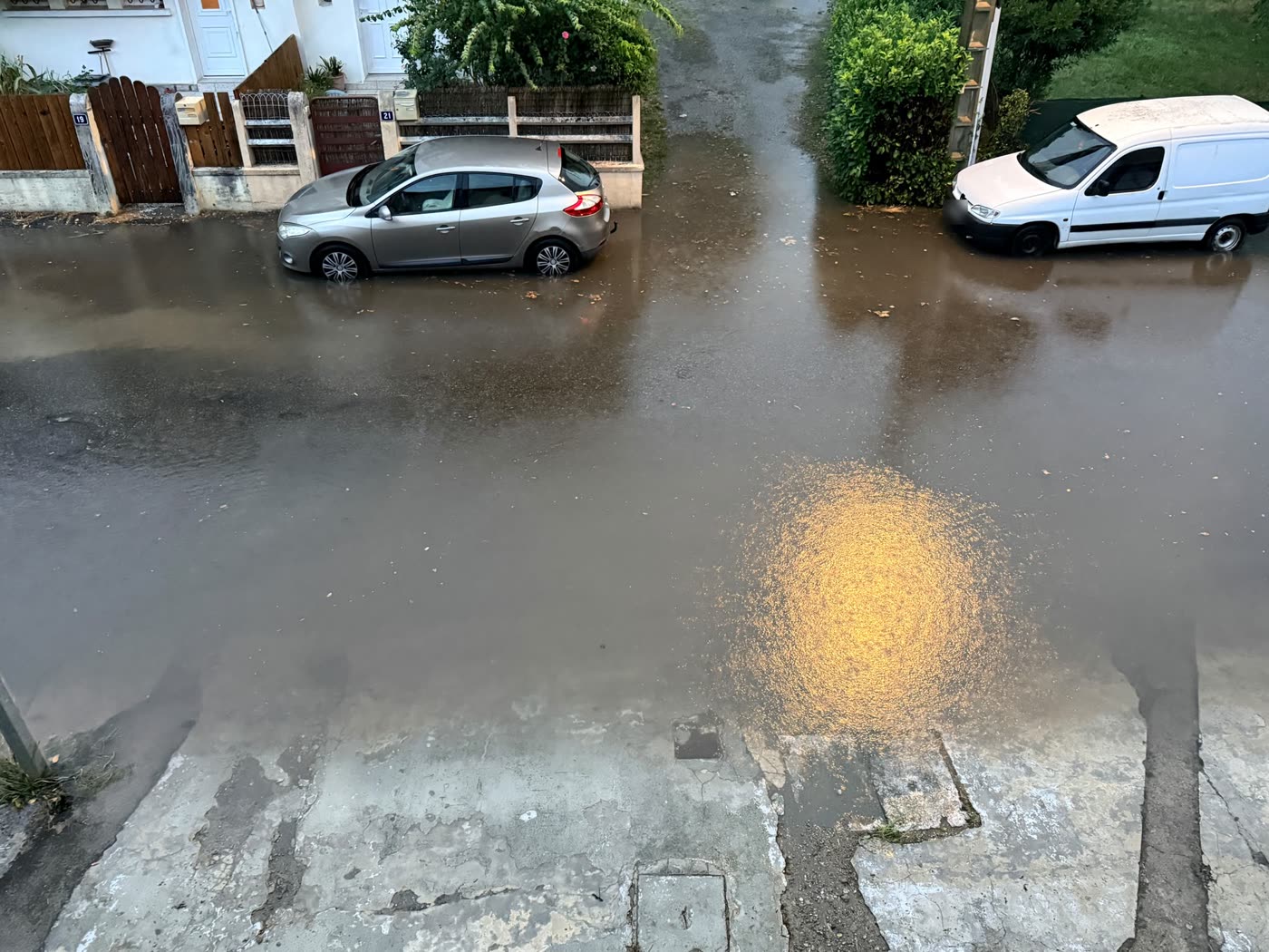 Eau montant jusqu'aux portails et aux boîtes aux lettres des habitations rue de la Poste à Gourdan-Polignan, 20 août 2026