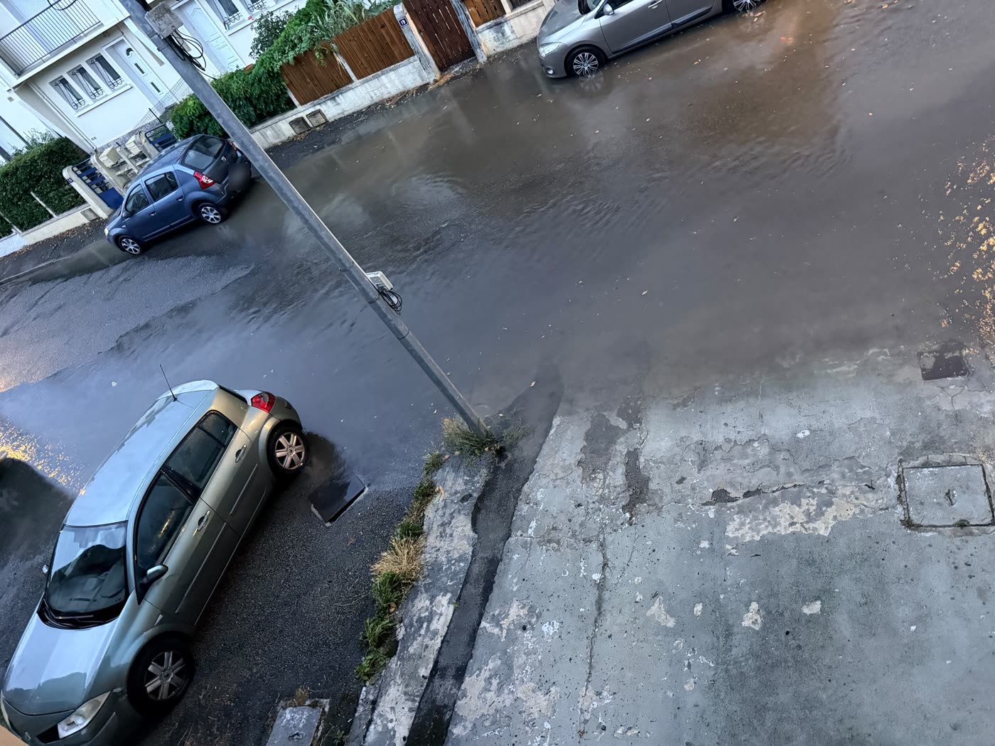 Voitures stationnées les roues dans l'eau rue de la Poste à Gourdan-Polignan pendant l'inondation du 20 août 2026